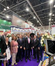 Administrator Daniel B. Whitley and U.S. Deputy Chief of Mission Eric Gaudiosi stand together with FAS overseas staff at the Gulfood 2025 trade show. The group poses in front of an exhibition booth featuring trade materials and promotional banners